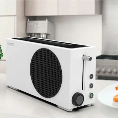 A white toaster with a black circular grill on the side, resembling an Xbox Series S console, sits on a kitchen counter.