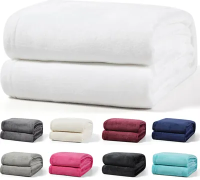 A collage of folded blankets in various colors, with two large white blankets at the top.