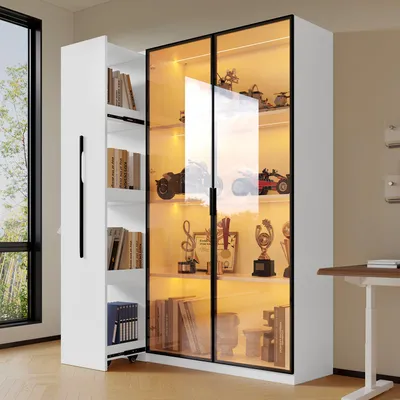 A white display cabinet with glass doors and LED lighting, showcasing various items on its shelves. A smaller white cabinet with shelves of books is attached to the left side.