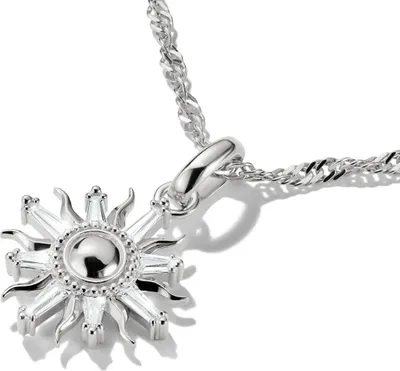 A close-up shot of a silver sun-shaped pendant necklace on a white background.
