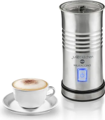 A stainless steel milk frother and a cup of cappuccino are shown against a white background.