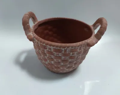 Kleines aus Terrakotta gefertigtes Gefäß mit zwei Henkeln. Es ist rund und hat geflochtene Textur.