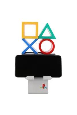A black smartphone is held upright by a white stand, which is topped by a colorful PlayStation controller button-shaped accessory.