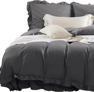 A close-up view of a bed with dark gray bedding and two pillows.
