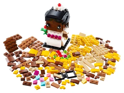A LEGO BrickHeadz bride figure surrounded by loose LEGO bricks of various colors and shapes.