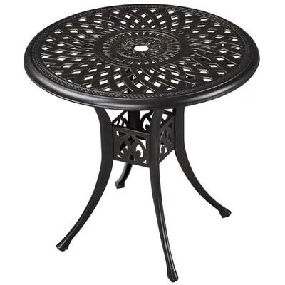 A round metal garden table with an ornate, patterned top and three curved legs.