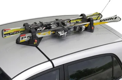 A ski rack with skis attached to the roof of a silver car.