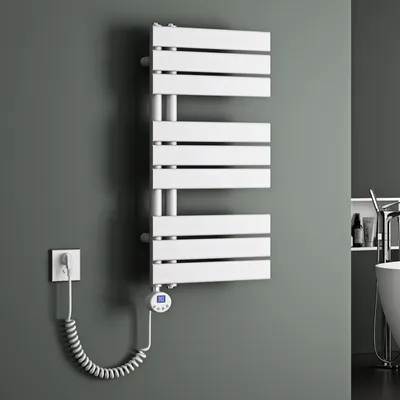 A white electric towel radiator mounted on a gray wall, with a coiled power cord connected to a wall outlet and a small digital controller.