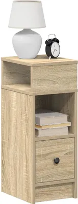 A bedside table with a lamp and an alarm clock on top, and books inside the shelf.