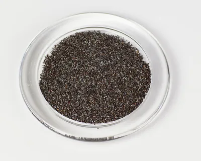 Poppy seeds are shown in a clear glass dish against a white background.
