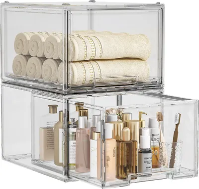 Two clear acrylic storage drawers stacked, one filled with rolled towels, the other with various toiletries.