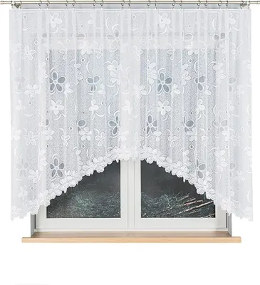 A white lace curtain with a floral pattern hangs over a window.