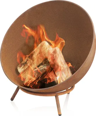 A round, rusty-looking fire pit with logs and flames inside, resting on three legs.