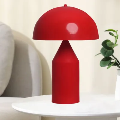 A red mushroom-shaped table lamp is displayed on a white table.