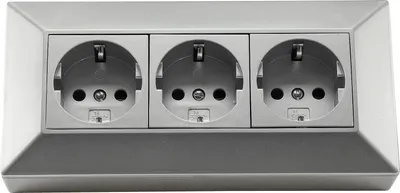 A silver-colored triple electrical socket outlet mounted on a wall.