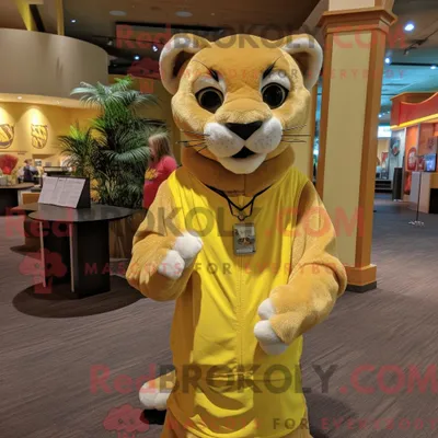Productafbeelding van Mascottekarakter REDBROKOLY van een gele bergleeuw gekleed met een jumpsuit en sjaalspelden