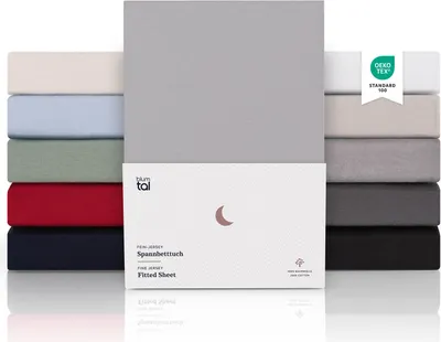 A stack of folded fitted sheets in various colors, with a product box in the foreground.