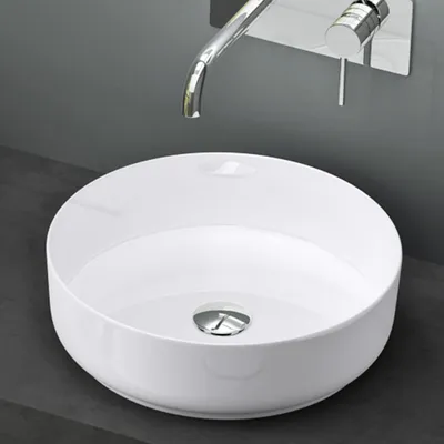 A white ceramic sink with a chrome faucet mounted on a gray wall.