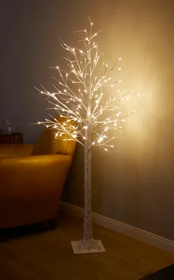 A lit LED tree in a room, next to a sofa.