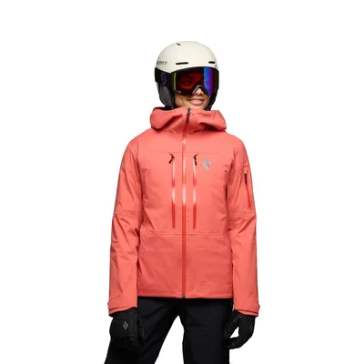Dame trägt die Recon Stretch LT Shell Jacke von Black Diamond in leuchtendem Korallenrot; ausgestattet mit Helm und Skibrille.