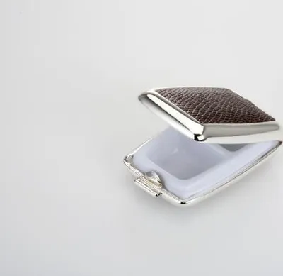 A pill box with a textured brown lid and a silver frame is shown open against a white background.