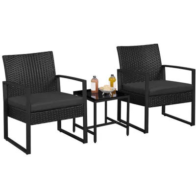 Two black rattan chairs and a small black table with drinks and snacks on a white background.