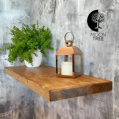 A wooden shelf with a plant and a lantern on it, mounted on a textured wall.