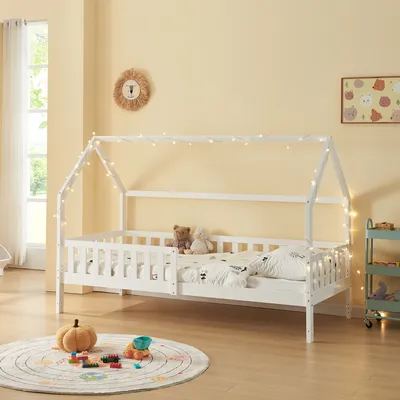 A child's bedroom with a white house bed decorated with fairy lights.