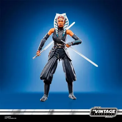 A Star Wars action figure of Ahsoka Tano posed with two lightsabers against a blue background.