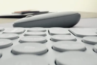 A close-up, low-angle shot of a keyboard with a computer mouse in the background.