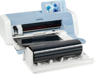 A Brother ScanNCut cutting machine with a roll holder and a roll of material loaded.