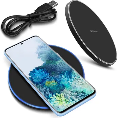 A smartphone is placed on a wireless charger, with a USB cable in the background.