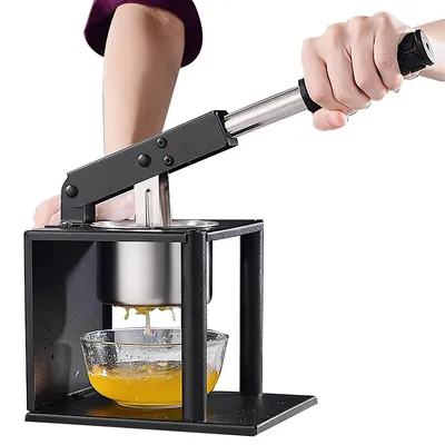 A person is using a manual fruit juicer to extract juice into a glass bowl.