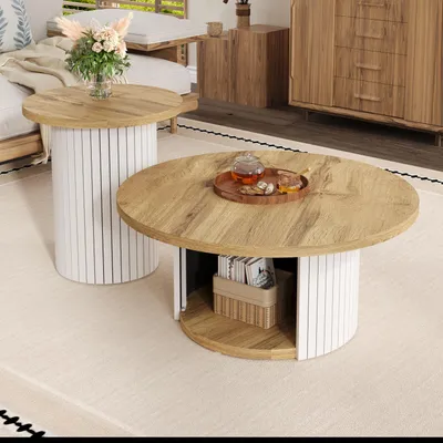 A living room scene featuring two round coffee tables with wooden tops and white ribbed bases, placed on a textured rug.