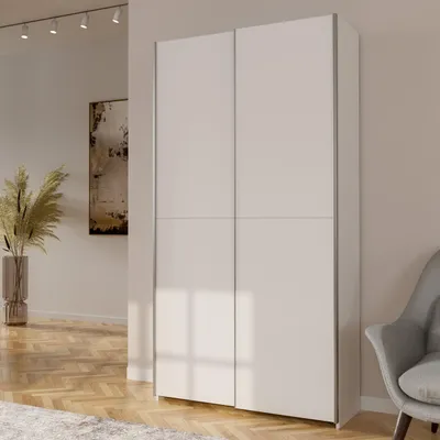 A modern living room with a large white wardrobe, a painting on the wall, and a chair.