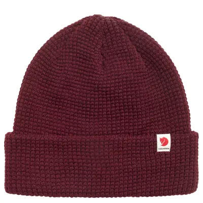 A maroon knitted hat with a small white logo patch on the front.