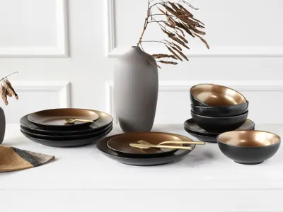 A table setting with plates, bowls, and a vase.