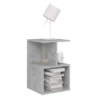 A modern, minimalist bedside table with a concrete-grey finish, featuring a lamp, a reed diffuser, and an alarm clock.