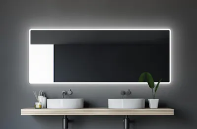 A modern bathroom vanity with two sinks and a large illuminated mirror.