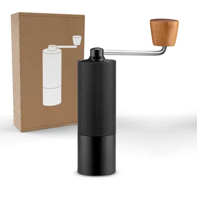 A black manual coffee grinder with a wooden handle is shown next to its brown cardboard packaging, which has a white illustration of the grinder.