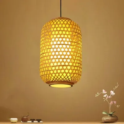 A hanging lamp made of bamboo is shown in the center of the image against a plain brown background. A small vase with flowers is on the right side of the table.