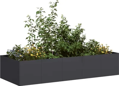A long, dark gray planter box filled with various plants, including tall green trees and smaller yellow and blue flowers.