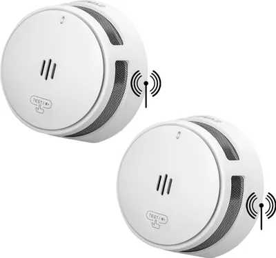 Two white wireless interconnected smoke detectors are shown against a white background. Each smoke detector has a 'TEST/HUSH' button and ventilation slots. A wireless signal icon is depicted next to each device.