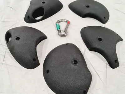 Klettergriffe Essentials Set 4 von Greenholds; fünf schwarze Klettergriffe und ein Karabiner.