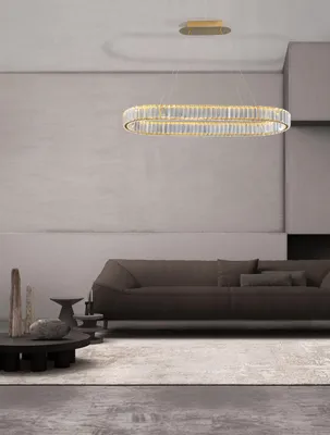 A modern living room with a sofa, coffee table, and a striking oval chandelier.