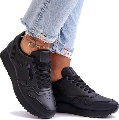 A person wearing ripped jeans and black sneakers.