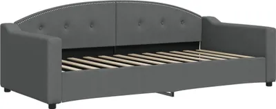 A dark gray fabric daybed with a curved, tufted headboard and wooden slats for the mattress support.