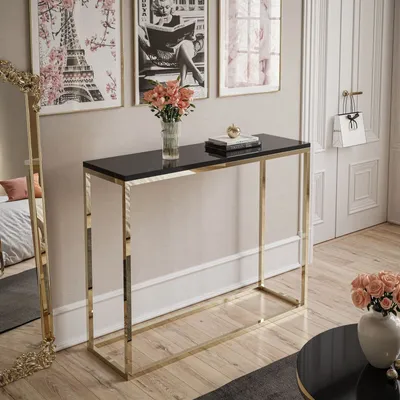 A console table with a black top and gold frame is placed in a room with artwork on the wall and a mirror.