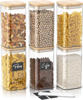 Six clear glass storage jars with bamboo lids, filled with various food items and labeled.