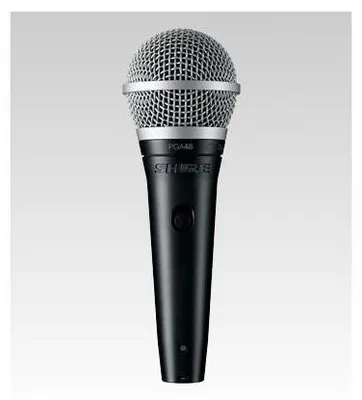 A studio shot of a black Shure microphone against a light gray background.
